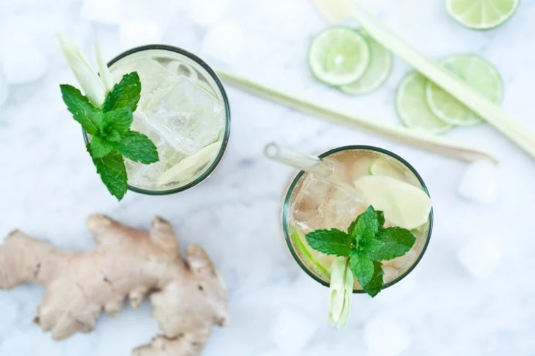 Dva sklenice zázvorové limonády s mátou, citronovou trávou a čerstvým zázvořem.