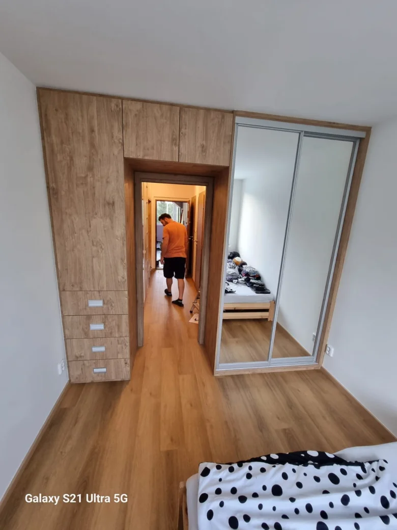 Dřevěná skříň s posuvnými zrcadlovými dveřmi a šuplíky v ložnici