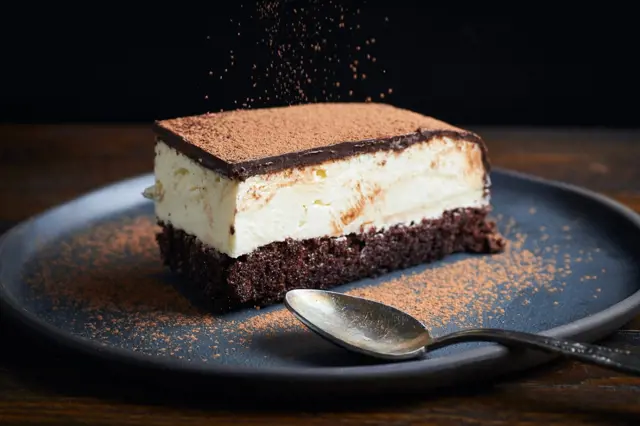 Kousek dortu Tiramisu posypaný kakaem.