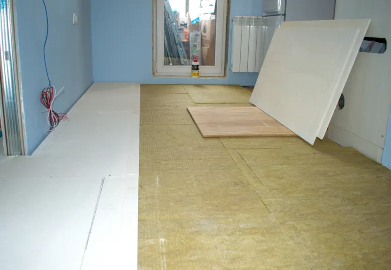 Zateplovací minerální vlna položená na podlahu s bílými deskami.