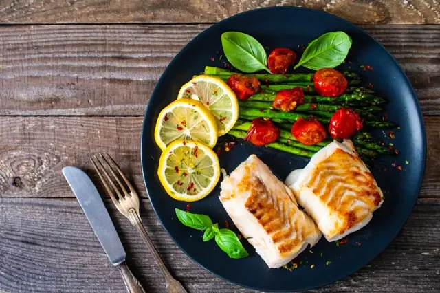 Grilovaný pangasius s asparginem na talíři.