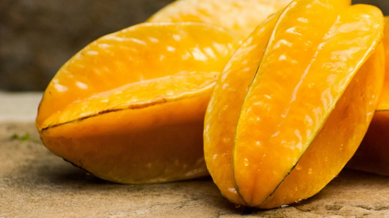 Žlutá karambola nakrájená na kusy s lesklou dužinou.