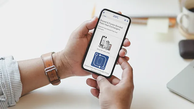 Ruka drží chytrý telefon s aplikací o výměníku tepla.