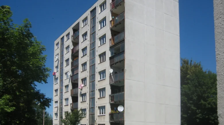 Vysoký bytový dům s balkony na modré obloze.