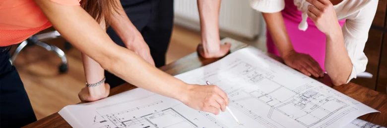 Architekti projednávají plán moderního domu u stolu.
