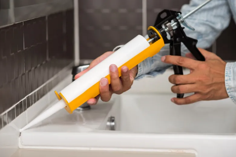 Náplast aplikuje sanitární silikon do vany.
