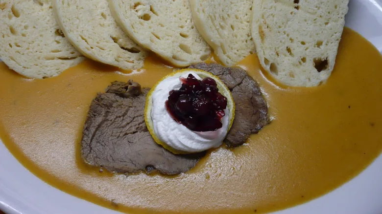 Hot svíčková s brusinkami na bílém talíři.