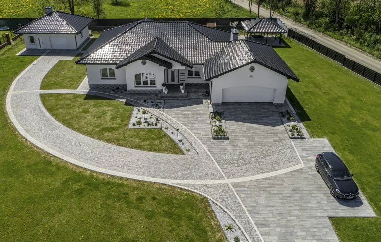 Pěšina kolem domu s kamenem a zelenou trávou