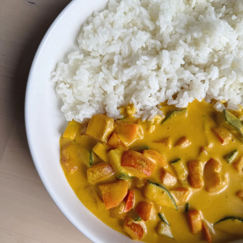 Bílé rýže s žlutou vegetariánskou kari omáčkou.