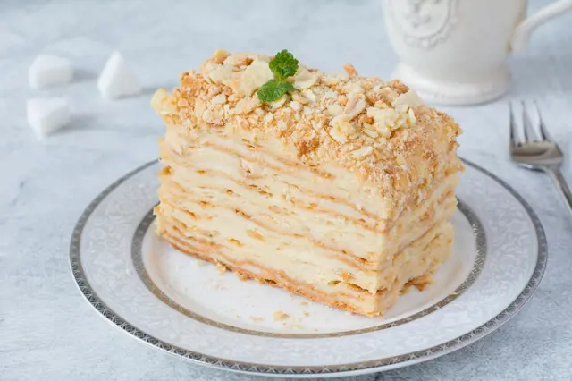Kousek dortu napoleon z listového těsta s ořechy.