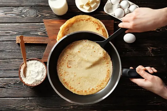 Připravování palačinek s moukou, vejci a máslem.
