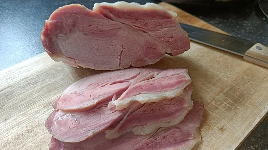 Nakrájené uzené maso na dřevěném prkénku