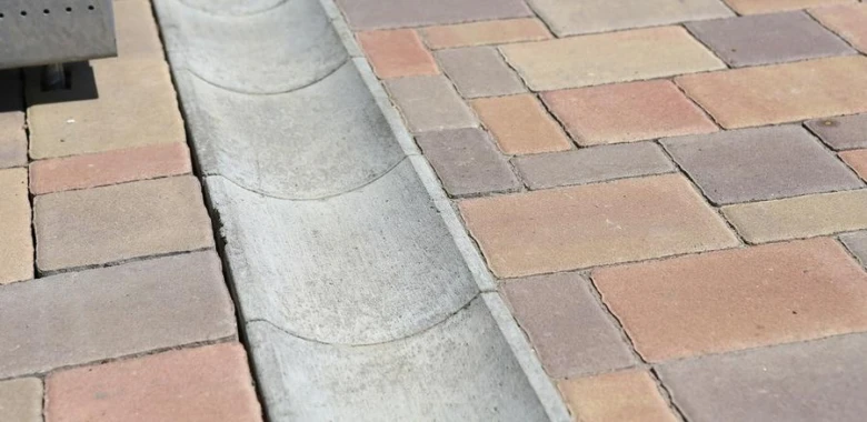 Drenážní žlóbek mezi dlaždicemi na chodníku