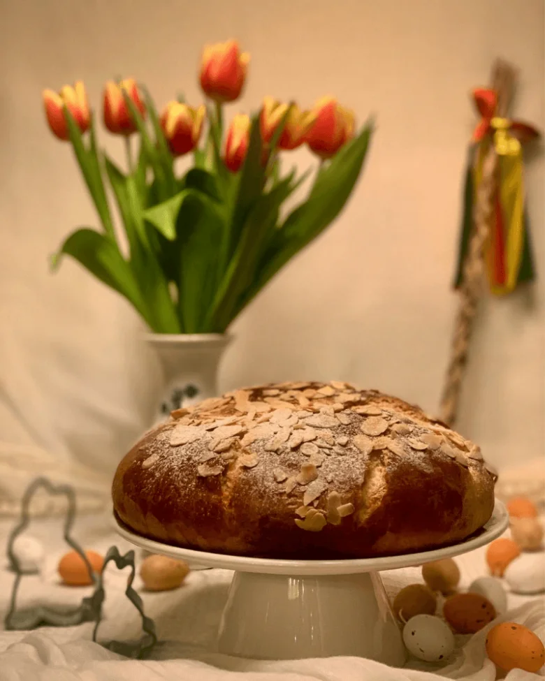 Velikonoční chléb s mandlemi, vejci a tulipány v pozadí.