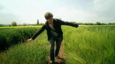 Muž kráčí po poli mezi vysokými zelenými plodinami.