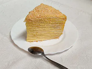 Kousek dortu Napoleon z listového těsta na talíři.