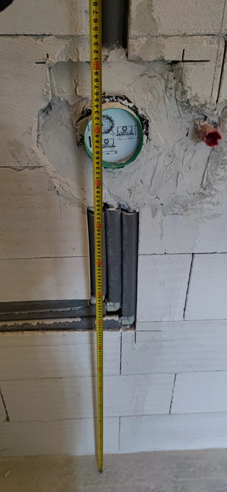 Instalace topení v domě s měřicí páskou a izolací.