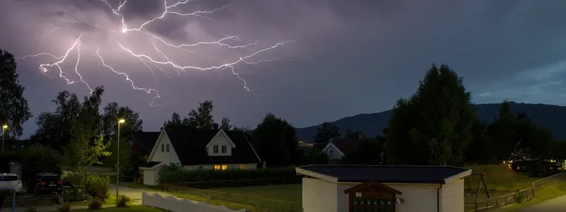 Blesk nad domy ukazuje nutnost správného uzemnění hromosvodu.