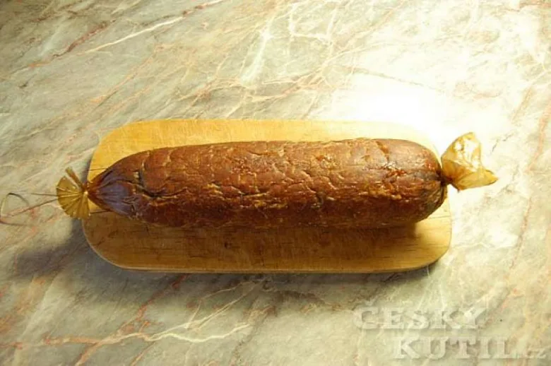 Hotový domácí uzený salám na dřevěném prkénku.