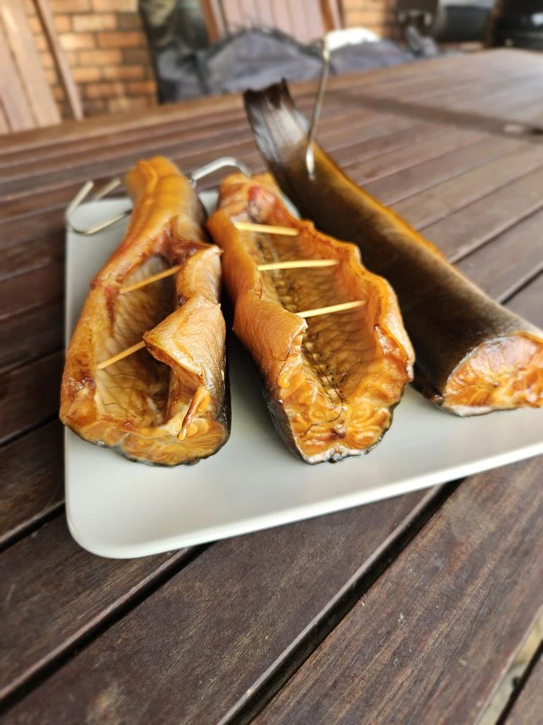 Uzená kapra na talíři s dřevěnými špejlemi