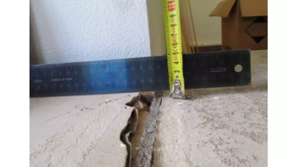 Měření šířky štěrbiny mezi betonovými deskami před zateplením podlahy.