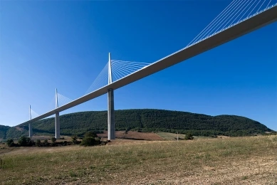 Fotografie viaduktu Millau přes údolí s kopci na pozadí.