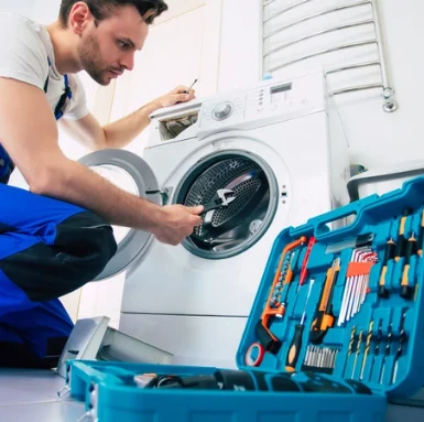 Technik opravuje pračku pomocí klíče s otevřenou náradní skříňkou.