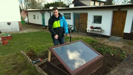 Muž ukazuje stavbu venkovního parníku v zahradě.
