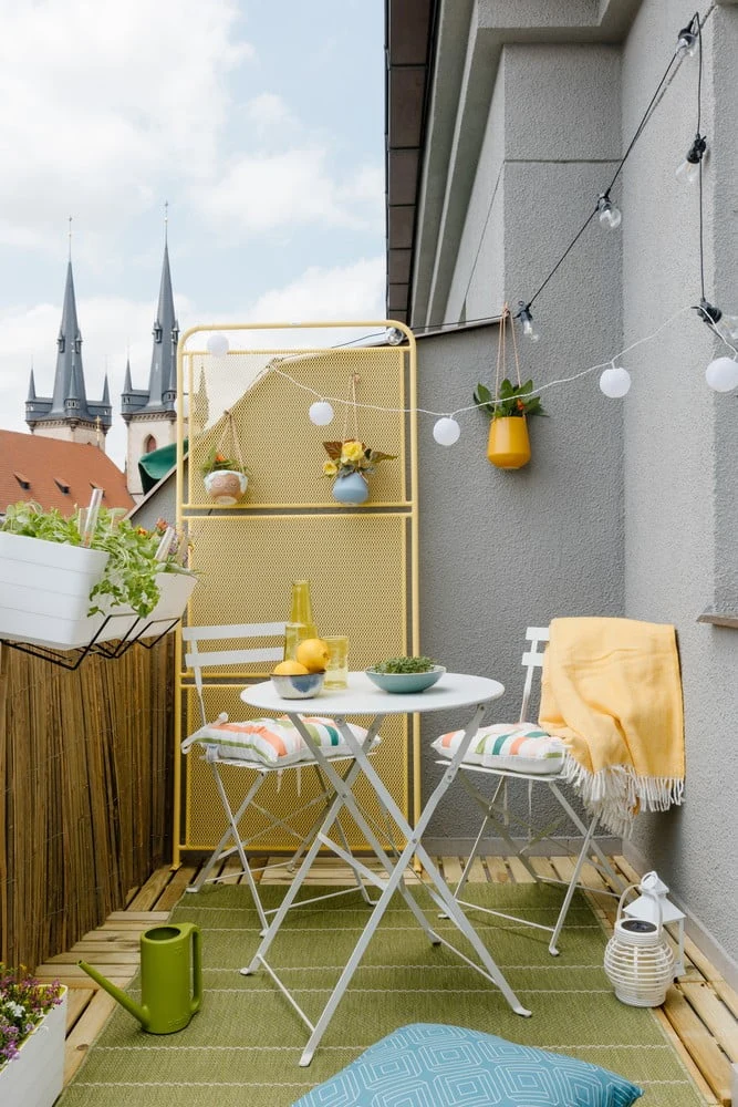 Stylová terasa s bílým stolečkem, židlemi a zelenou podložkou
