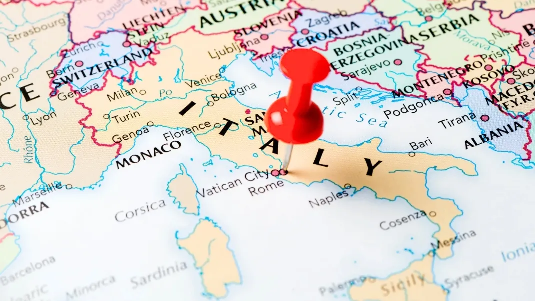 Fyzická mapa Evropy s červenou jehlou na Itálii pro zeměpisný kvíz.
