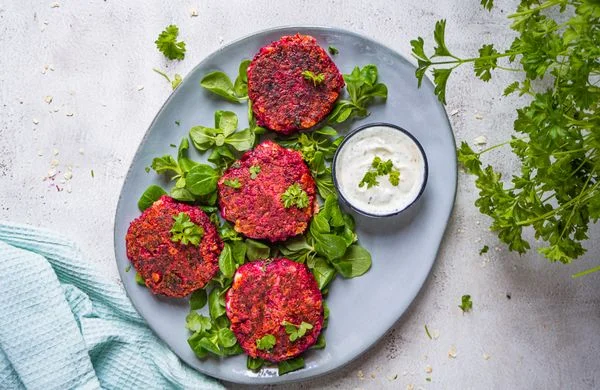 Čtyři vegetariánské bramborové placky s dipem na listech špenátu.