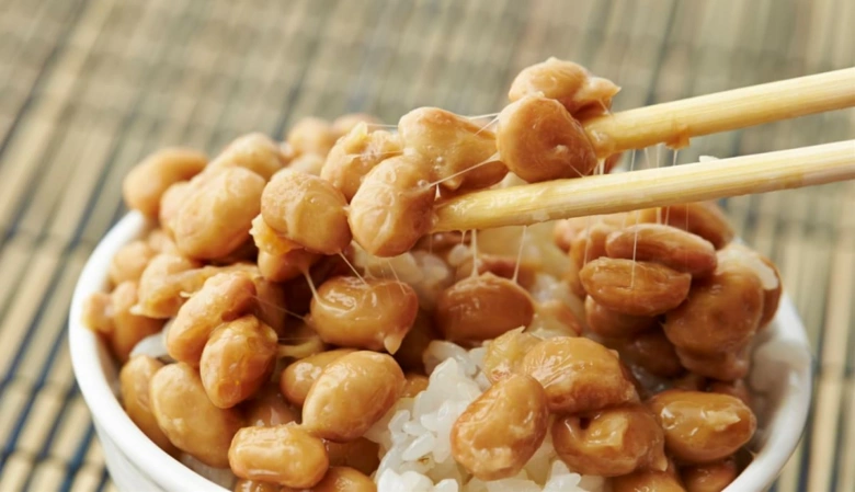 Fermentované sójové boby natto na rýži s bambusovými špejlí.