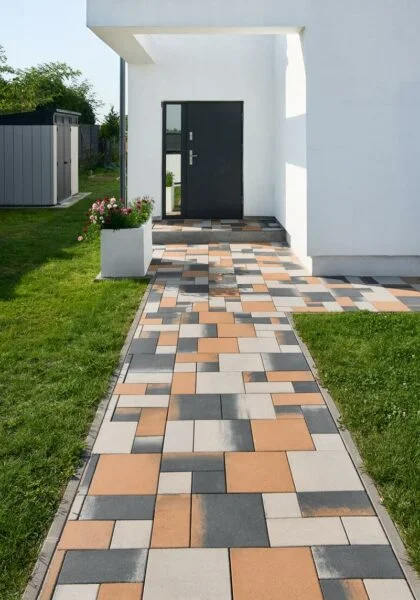 Moderní chodník kolem domu s barevnými dlaždicemi